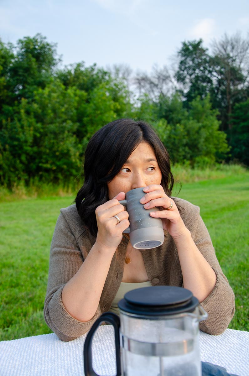 woman sipping from a mug outdoors